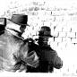 Worker in trillby hat at base of brick stack